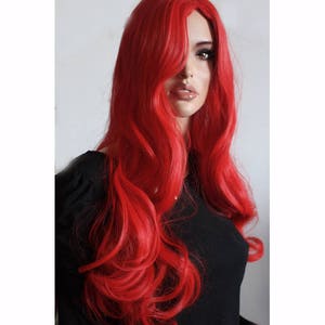Puede incluir: Una peluca larga, ondulada y de color rojo brillante con raya lateral. La peluca est&aacute; peinada con rizos sueltos y cae hasta los hombros.