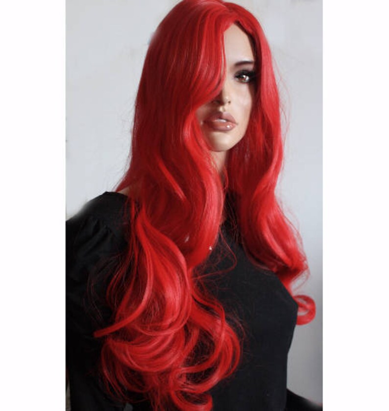 Puede incluir: Una peluca larga, ondulada y de color rojo brillante con raya lateral. La peluca est&aacute; peinada con rizos sueltos y cae hasta los hombros.