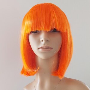 May include: A vibrant orange wig with a blunt fringe and a bob cut. The wig is styled on a mannequin head, showcasing its bright color and sleek design. The wig's bold color makes it suitable for costume parties or theatrical performances.