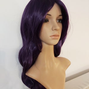 May include: A long, wavy purple wig with a side part. The wig is styled with loose curls and falls to the shoulders.