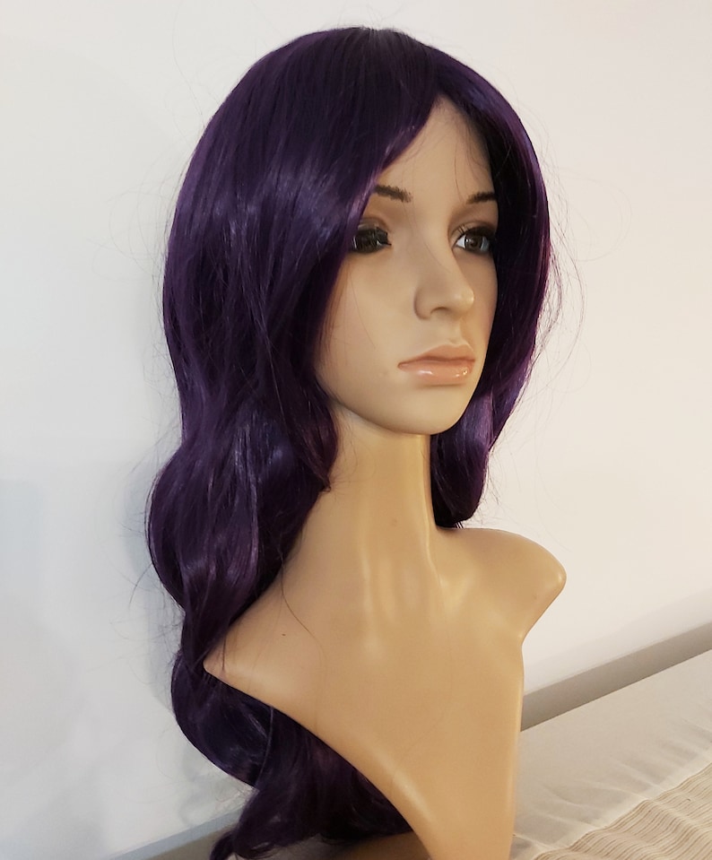 May include: A long, wavy purple wig with a side part. The wig is styled with loose curls and falls to the shoulders.