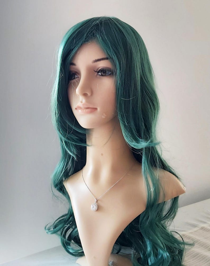 May include: A long, wavy, teal green wig with a side part. The wig is styled with loose curls and is worn on a mannequin head.