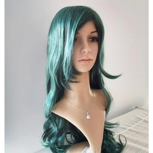 May include: A long, wavy teal green wig with a side part. The wig is styled with loose curls and is worn on a mannequin head.