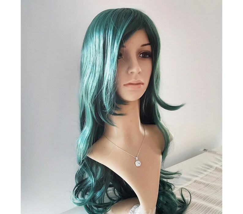 May include: A long, wavy teal green wig with a side part. The wig is styled with loose curls and is worn on a mannequin head.