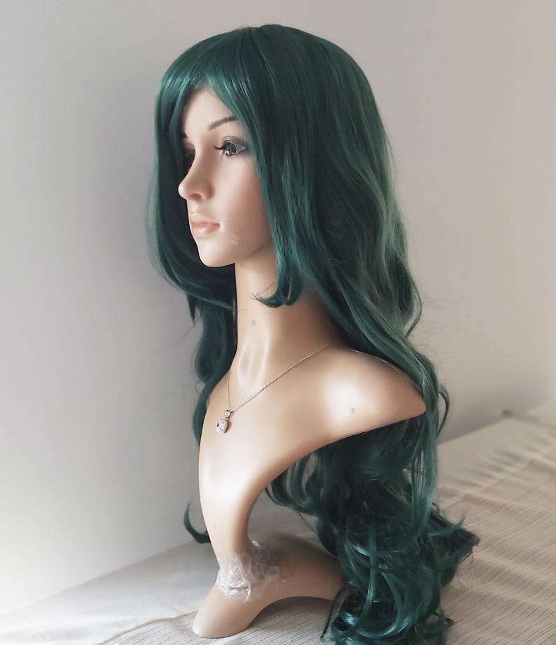 May include: A long, wavy, dark green wig with a side part. The wig is styled in loose curls and is worn on a mannequin head.