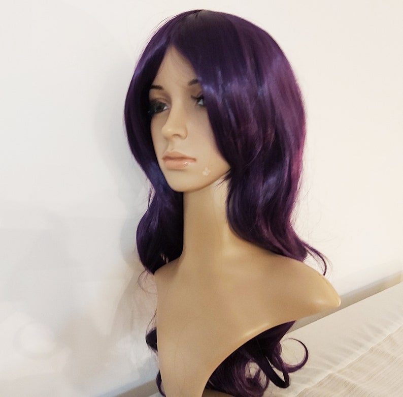 May include: A long, wavy purple wig with side-swept bangs. The wig is made of synthetic hair and is styled in a casual, everyday look.