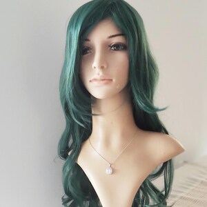 May include: A long, wavy, dark green wig with a side part. The wig is styled with loose curls and is worn on a mannequin head.