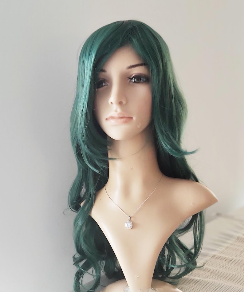 May include: A long, wavy, dark green wig with a side part. The wig is styled with loose curls and is worn on a mannequin head.