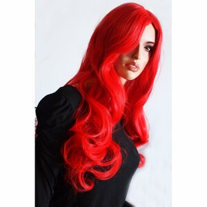 Puede incluir: Una peluca larga, ondulada, de color rojo brillante con raya lateral. La peluca est&aacute; peinada con rizos sueltos y cae hasta los hombros.