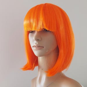 A vibrant red orange bob wig with bangs for women. High quality smooth synthetic short straight hair.