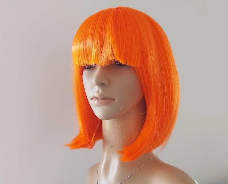 A vibrant red orange bob wig with bangs for women. High quality smooth synthetic short straight hair.
