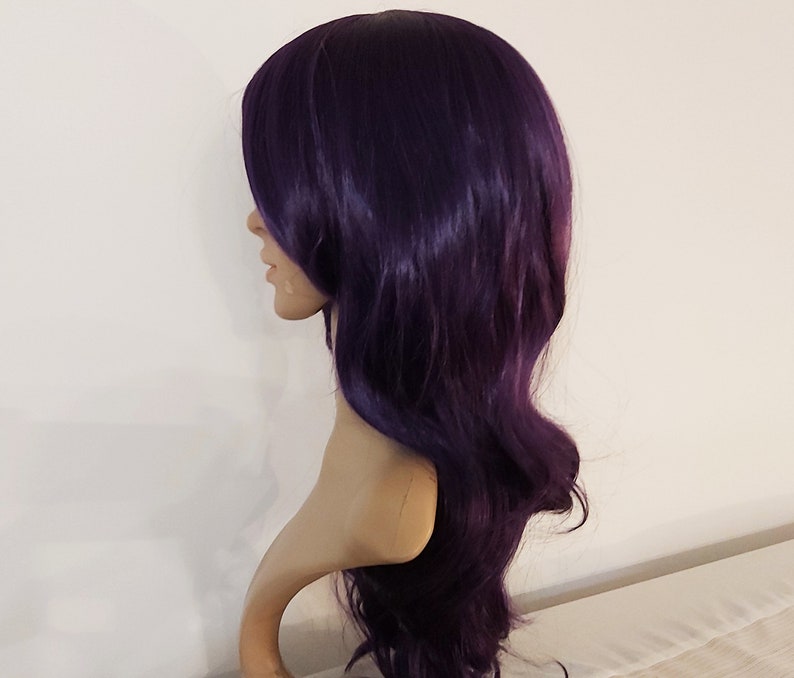 May include: A long, wavy, dark purple wig with a side part. The wig is styled with loose waves and falls to the shoulders.