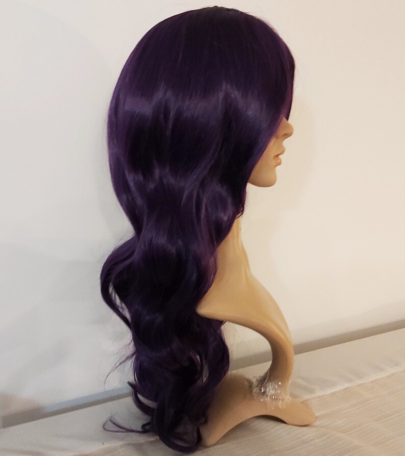 May include: A long, wavy, purple wig on a mannequin head. The wig has a side part and is styled in loose waves.