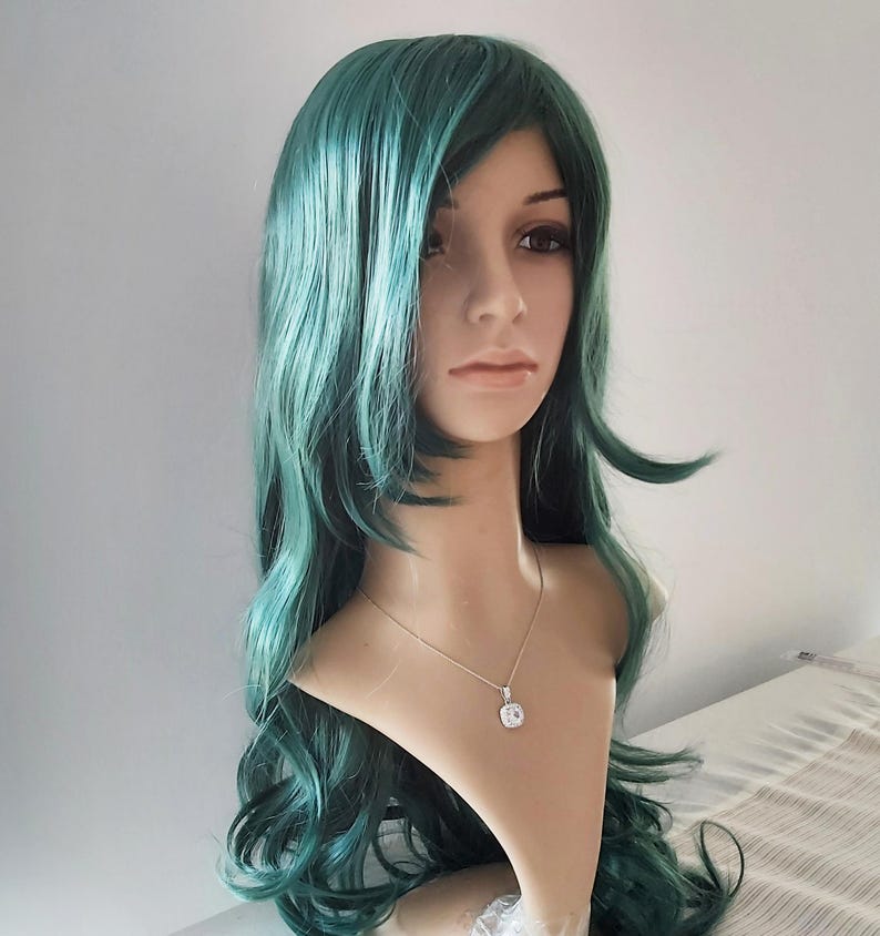May include: A long, wavy, teal green wig with a side part. The wig is styled with loose waves and falls to the shoulders.