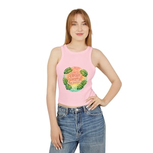 May include: A light pink tank top with a round graphic that says "Practice Radical Empathy" surrounded by green leaves. The tank top is sleeveless and made of a soft material.