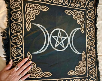 Può includere: Tovaglia da altare in tessuto nero con un bordo di nodo celtico dorato e un pentagramma bianco e un simbolo di luna tripla al centro.