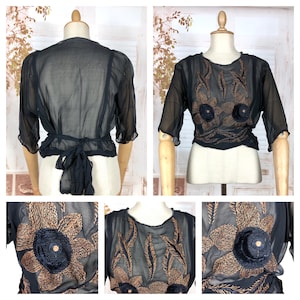 May include: Black sheer blouse with short sleeves and a tie-back waist. The blouse features intricate floral embroidery in shades of brown and navy blue. The design includes detailed flower appliques, creating a vintage-inspired look.