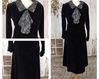 May include: A black velvet dress with a long sleeve and a plaid collar. The collar is tied in a bow at the neck.