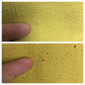 Pode incluir: Close-up de um tecido amarelo com uma pequena mancha laranja. O tecido tem uma textura tecida.