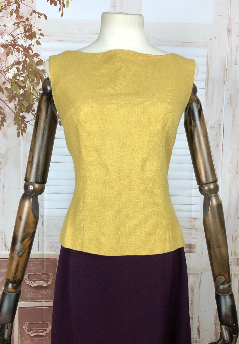 Pode incluir: Um top sem mangas amarelo mostarda com decote barco e corpo ajustado. O top &eacute; feito de um tecido texturizado e &eacute; combinado com uma saia bord&ocirc;.