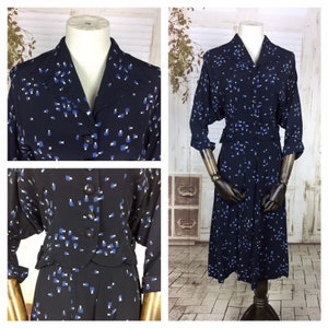Può includere: Un completo vintage blu navy composto da abito e giacca. L'abito presenta un colletto, una chiusura con bottoni e una gonna al ginocchio. La giacca ha un motivo coordinato di forme geometriche blu e bianche.