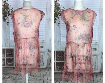 May include: A sheer pink floral dress with a gathered waist and cap sleeves. The dress is on a mannequin and has a label that reads "Collapsible Shoulder Studio One 6".