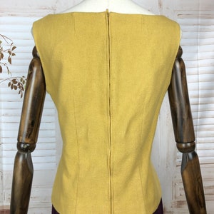 Pode incluir: Um top sem mangas amarelo mostarda com um z&iacute;per nas costas. O top &eacute; feito de um tecido texturizado e tem um design simples e cl&aacute;ssico.