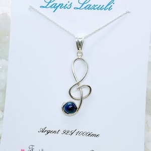 May include: A silver necklace with a blue lapis lazuli stone pendant shaped like a treble clef. The pendant is inscribed with "Argent 925/1000eme" and "Fait main avec Amour".