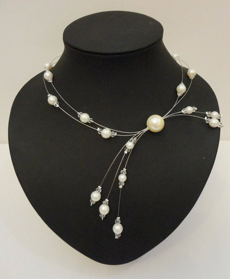 Peut inclure: Un collier d&eacute;licat en perles blanches avec un pendentif en perle plus grand et un design en cascade de petites perles.