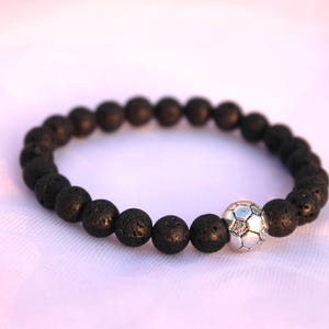May include: Black lava rock beaded bracelet with a silver football charm.