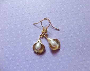 May include: A pair of gold earrings with a pearl drop in the shape of a flower.