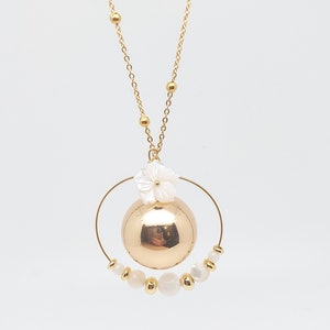 Pu&ograve; includere: Una collana d'oro con un ciondolo rotondo d'oro e un ciondolo a forma di fiore bianco. Il ciondolo &egrave; circondato da un cerchio di perle bianche.