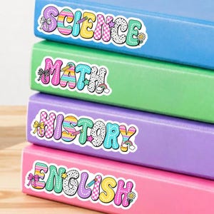 May include: A stack of four hardcover books in blue, green, purple, and pink. Each book features a colorful, patterned sticker on the spine with the text SCIENCE, MATH, HISTORY, and ENGLISH in a playful, multi-colored bubble font with small icons.