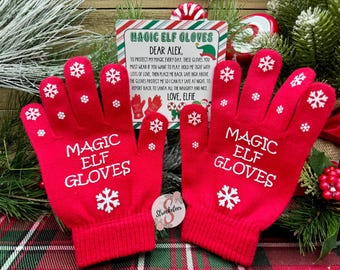 May include: A pair of bright red Magic Elf Gloves with white snowflake accents and text. The gloves are displayed with a holiday-themed card that reads "Magic Elf Gloves" and a message to Alex.