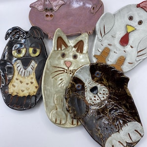 May include: Five ceramic dishware pieces shaped like animals. The dishes are a pink pig, a white chicken, a brown and white dog, a white cat, and a brown and white owl.
