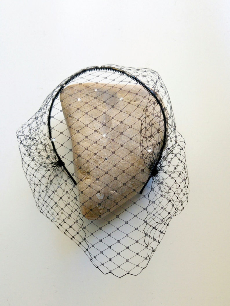 May include: Black birdcage veil with a black headband. The veil is made of a fine mesh material and has a delicate, feminine look.