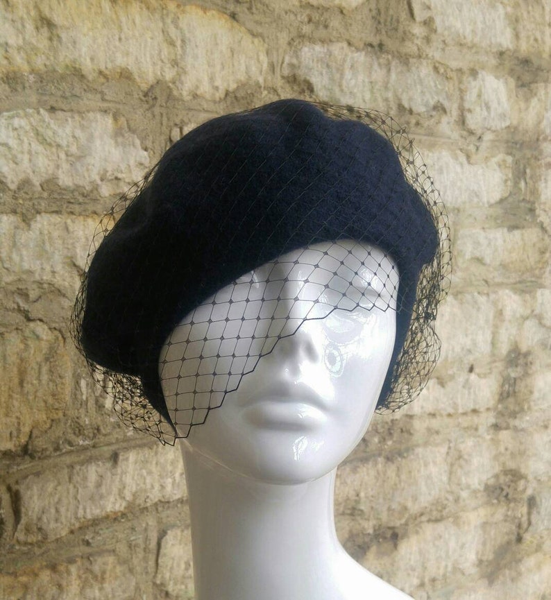 May include: A navy blue beret with a black tulle veil. The beret is made of felt and has a classic shape.