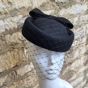 Schwarzer Pillbox Hut mit Birdcage Fascinator Schleier schwarzes Wollfilz Trauerhut Jackie Stil Hochzeitshut 1960er Hut