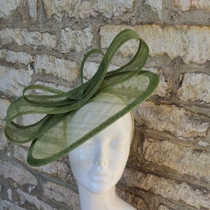 Pu&ograve; includere: Un cappello fascinator verde con un grande fiocco. Il cappello &egrave; realizzato in un materiale a rete fine ed &egrave; perfetto per un'occasione speciale.