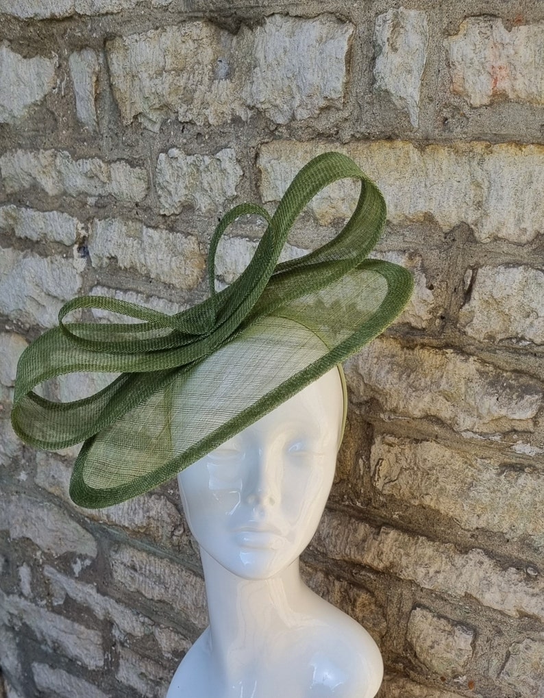 Pu&ograve; includere: Un cappello fascinator verde con un grande fiocco. Il cappello &egrave; realizzato in un materiale a rete fine ed &egrave; perfetto per un'occasione speciale.