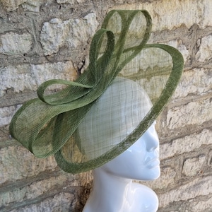 Pu&ograve; includere: Un cappello verde a tesa larga con un grande fiocco dello stesso materiale. Il cappello &egrave; fatto di un tessuto fine e a rete.
