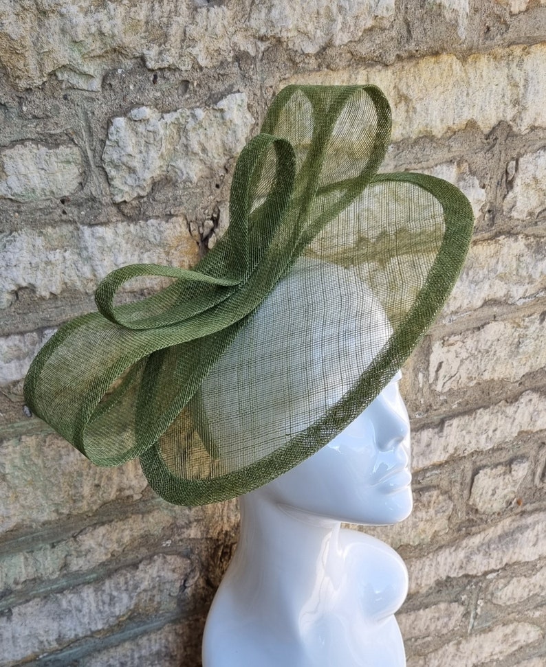 Pu&ograve; includere: Un cappello verde a tesa larga con un grande fiocco dello stesso materiale. Il cappello &egrave; fatto di un tessuto fine e a rete.