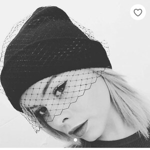 black and white image of young woaman in black smooth wool beanie hat with vintage 1940s style black fasciantor veil to front of hat covering eyes fashionable look for days or mourning