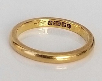 May include: A simple gold wedding band with a hallmark inscription on the inside of the band. The inscription reads "375 1212 57".