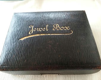 May include: A black leather jewel box with gold lettering that reads "Jewel Box".