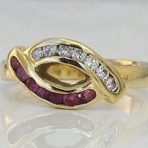Könnte beinhalten: Ein goldener Ring mit einem geschwungenen Design, besetzt mit kleinen roten Rubinen und weißen Diamanten.