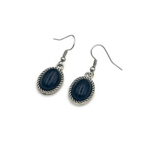 May include: A pair of silver earrings with black oval-shaped stones. The stones are set in a silver frame with a rope-like design.