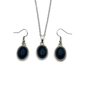 May include: A silver necklace and earrings set with black oval stones. The stones are set in a silver frame with a rope design.