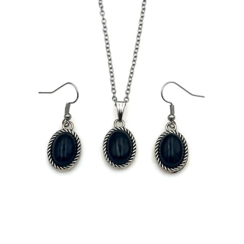 May include: A silver necklace and earrings set with black oval stones. The stones are set in a silver frame with a rope design.