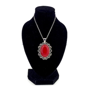 May include: A silver necklace with a red oval pendant set in a silver filigree frame.